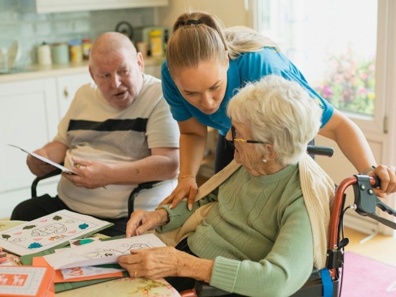 Caregiver assisting elderly couple with coloring