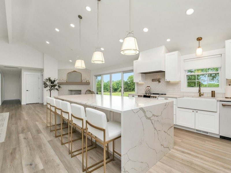 a large kitchen with a marble island and white cabinets