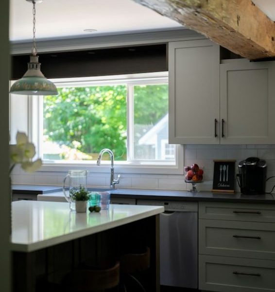 Bright kitchen interior with island, wooden beam, and green view