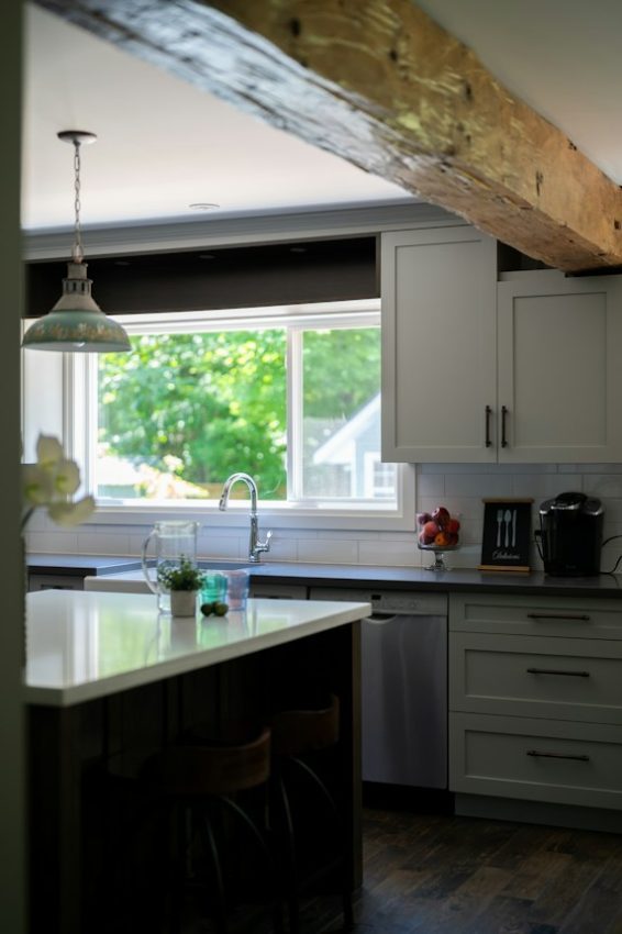 Bright kitchen interior with island, wooden beam, and green view
