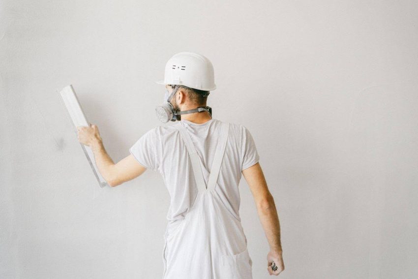 Contractor on full protective gear patching wall