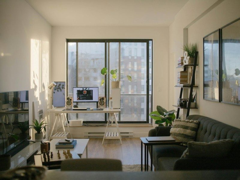 A sunlit home office with a desk, computer, and sofa in a living room